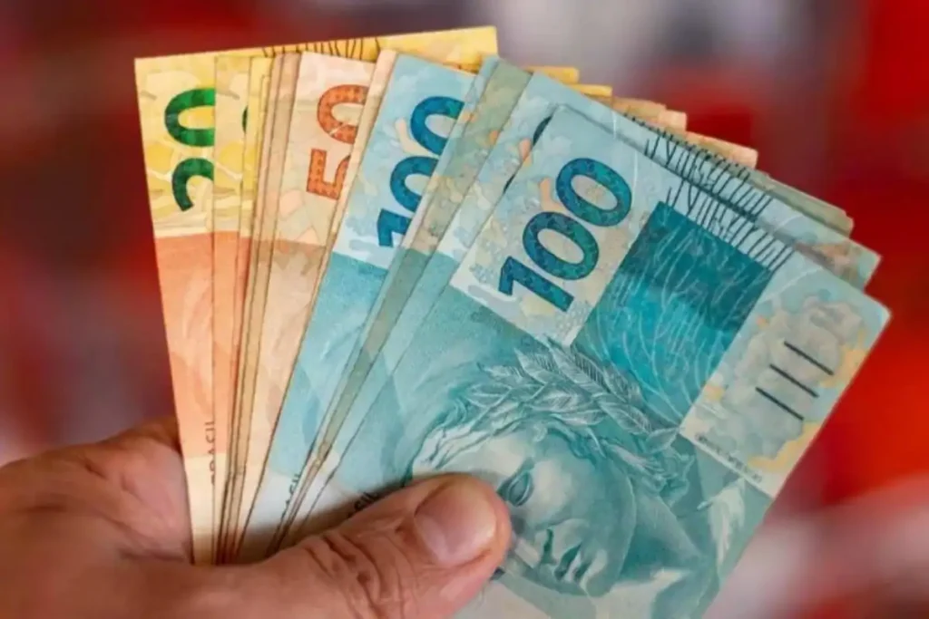 BMG inicia ressarcimento de R$ 7 milhões a aposentados por cobranças indevidas 1 Cédulas de dinheiro na mão de um aposentado, representando o ressarcimento do BMG
