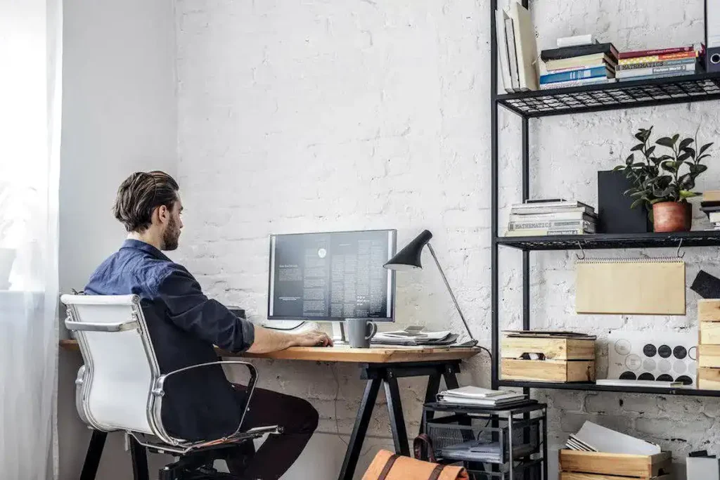 Profissional usando notebook em mesa com cadeira ergonômica no home office