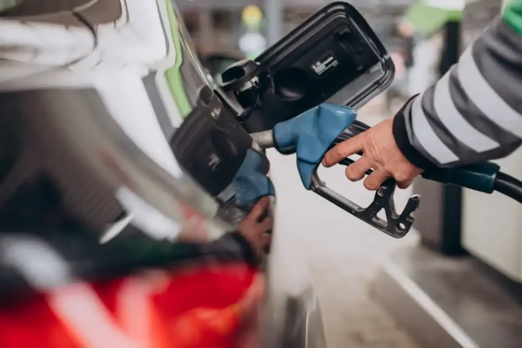 Mão abastecendo o tanque de um carro em um posto de gasolina.