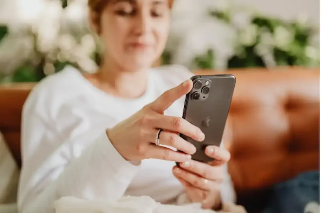 Mulher com telefone na mão se informando sobre compra de dólar.