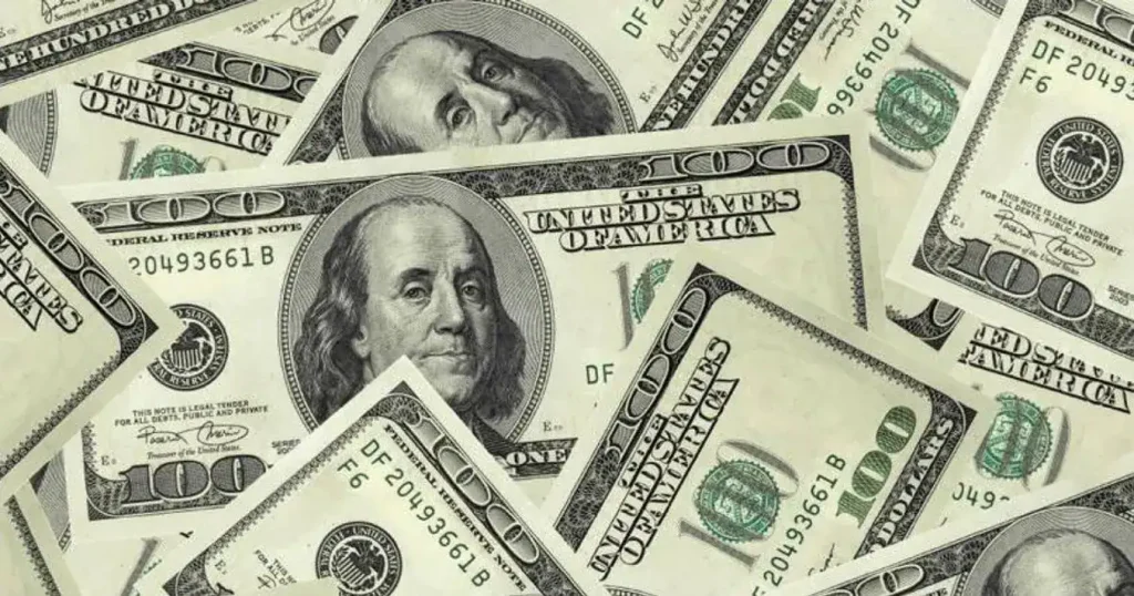 Notas de dólar e real sobre um gráfico financeiro em ascensão, simbolizando a valorização da moeda americana.