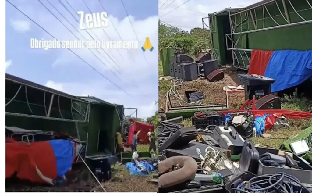Trio Elétrico Zeus, um caminhão grande com estrutura de palco, tombado de lado na margem de uma estrada de terra, com a parte superior virada para o chão. O veículo está em uma área rural, com vegetação ao redor, após acidente no trajeto para o Carnaval.