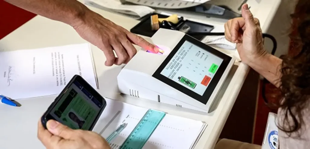 Eleitor em atendimento no Cartório Eleitoral para regularização de título e coleta de biometria, com documentos em mãos.