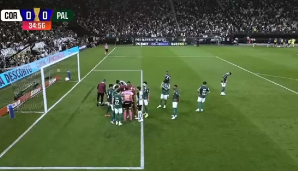 Andreas Pereira, jogador do Palmeiras, manipulando o gramado na marca do pênalti durante jogo contra o Corinthians na Neo Química Arena.