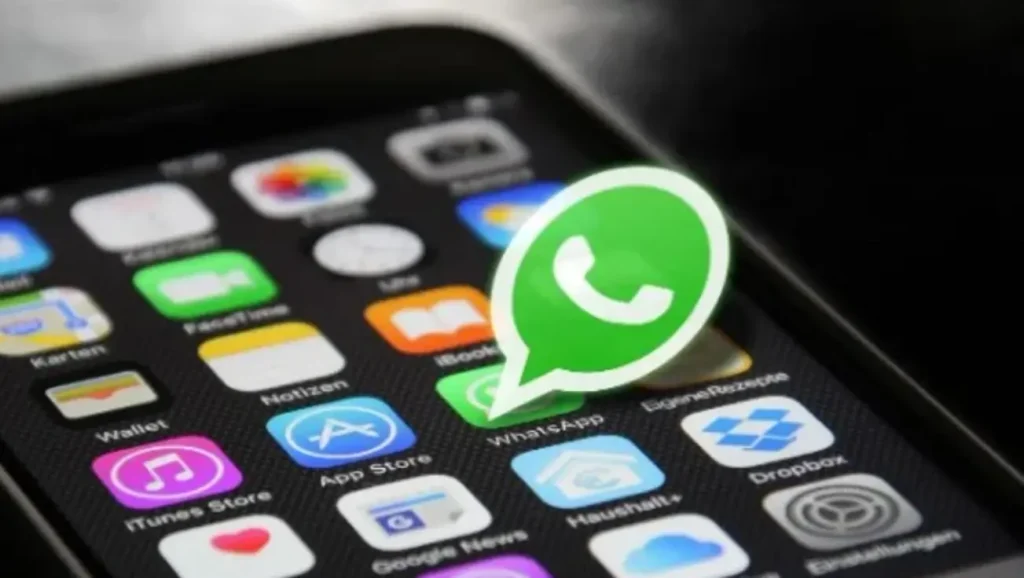 Mãos de um adulto e uma criança interagindo com um smartphone exibindo o aplicativo WhatsApp, simbolizando o controle parental.