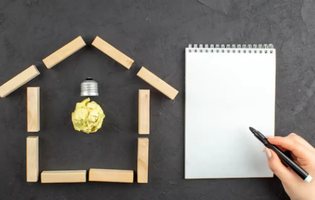 Vista superior da lâmpada idealight em casa em forma de casa bloco de notas marcador preto na mão feminina no preto