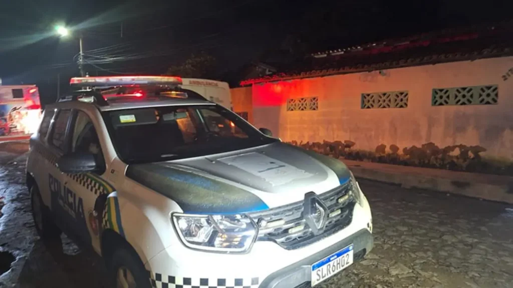 Viatura da Polícia Militar e do IML em frente à residência onde uma mulher foi assassinada a tiros no bairro Beira Mar, em Luís Correia (PI).