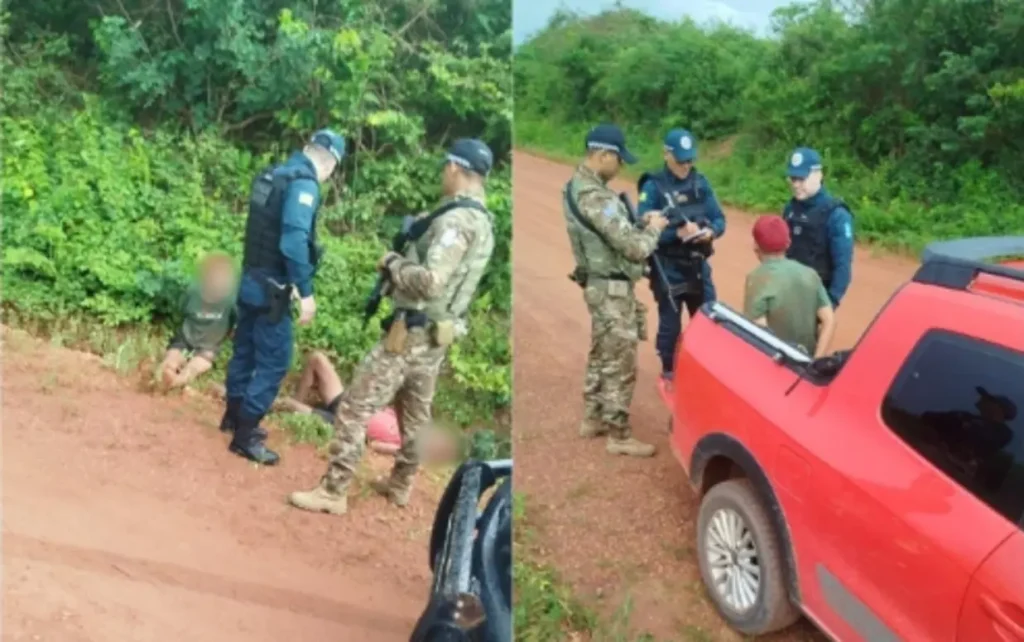 Dois policiais fardados de azul e um militar em uniforme camuflado abordam pessoa ajoelhada no chão em estrada de terra vermelha; em segundo plano, outros agentes consultam documentos próximo a veículo vermelho