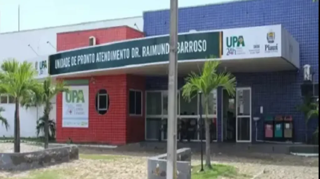 Fachada da Unidade de Pronto Atendimento (UPA) Dr. Raimundo Barroso, com paredes de azulejos vermelhos e azuis e palmeiras.