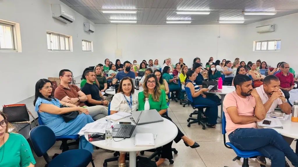 Crianças do 2º ano do ensino fundamental, sentadas em carteiras escolares, sorriem enquanto participam de uma atividade de leitura em uma sala de aula de Teresina.