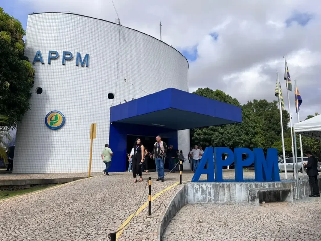 Fachada do prédio da Associação Piauiense de Municípios (APPM) em Teresina, com pessoas circulando na entrada em um dia nublado.