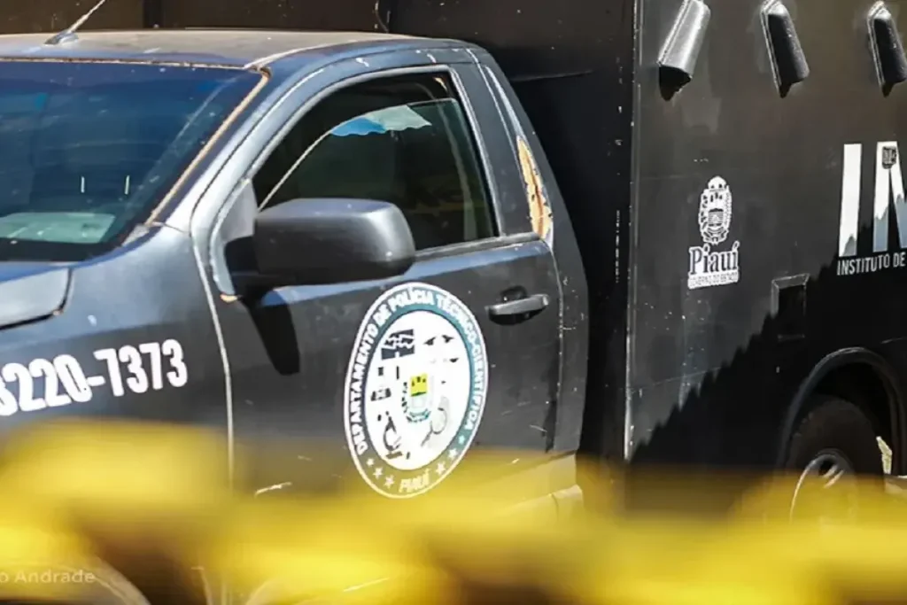 Caminhonete preta do Departamento de Polícia Técnico-Científica do Piauí com vidro da janela do motorista quebrado, exibindo o brasão oficial e número de telefone 3220-7373, com fita zebrada amarela em primeiro plano
