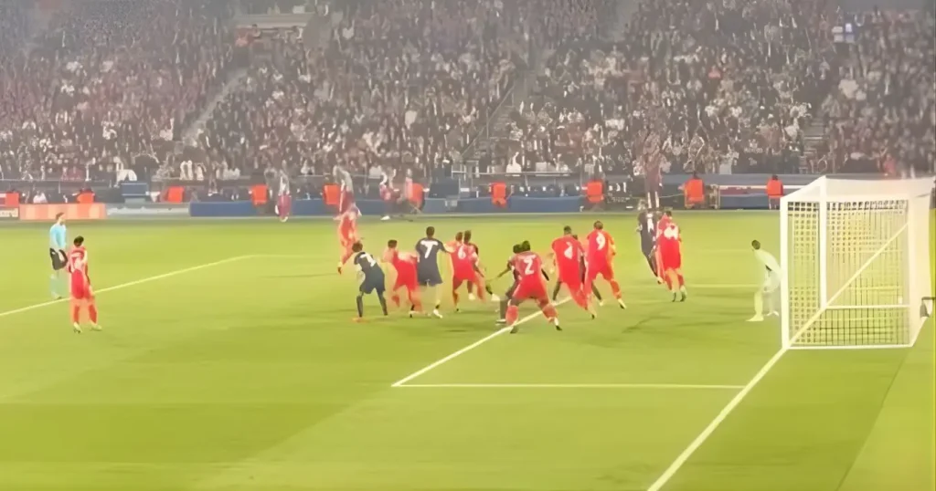 Jogador do PSG cobra falta contra barreira do Bayern de Munique em estádio lotado durante partida de futebol.