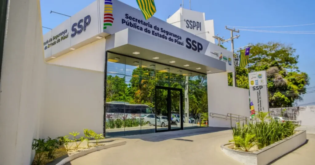 Fachada da Secretaria de Segurança Pública do Piauí (SSP-PI), um prédio branco e moderno com entrada de vidro, em um dia de sol.