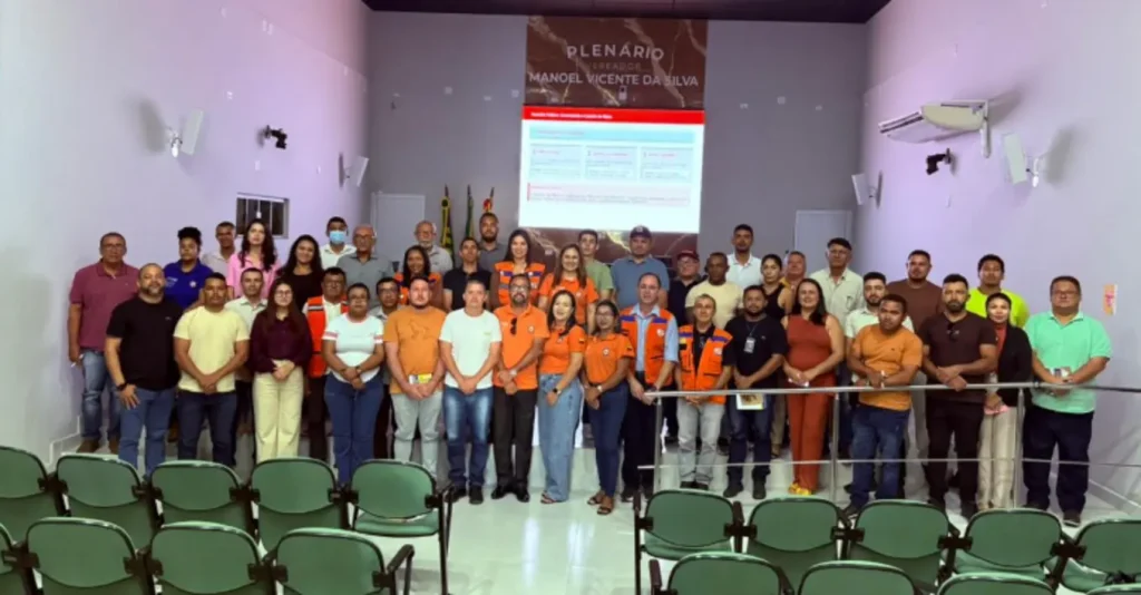 Defesa civil capacita municípios da região de floriano: Grupo de pessoas em plenário com telão e cadeiras