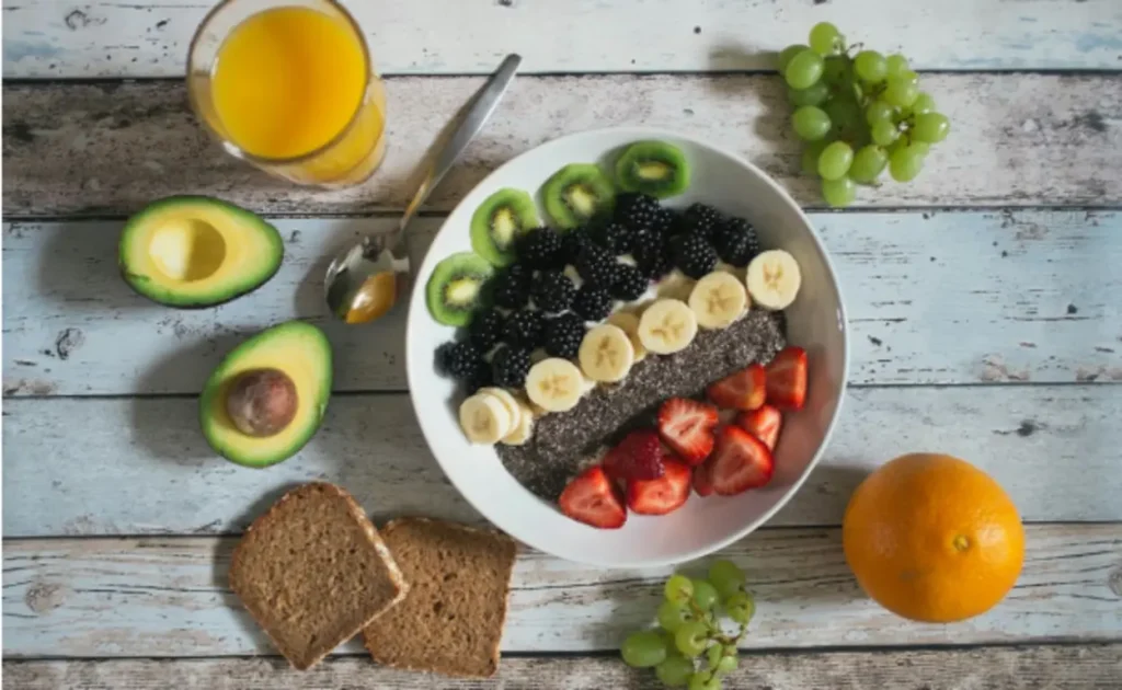 Bowl com frutas variadas, sementes de chia, abacate, pão integral e suco de laranja, representando alimentação equilibrada para emagrecimento e performance