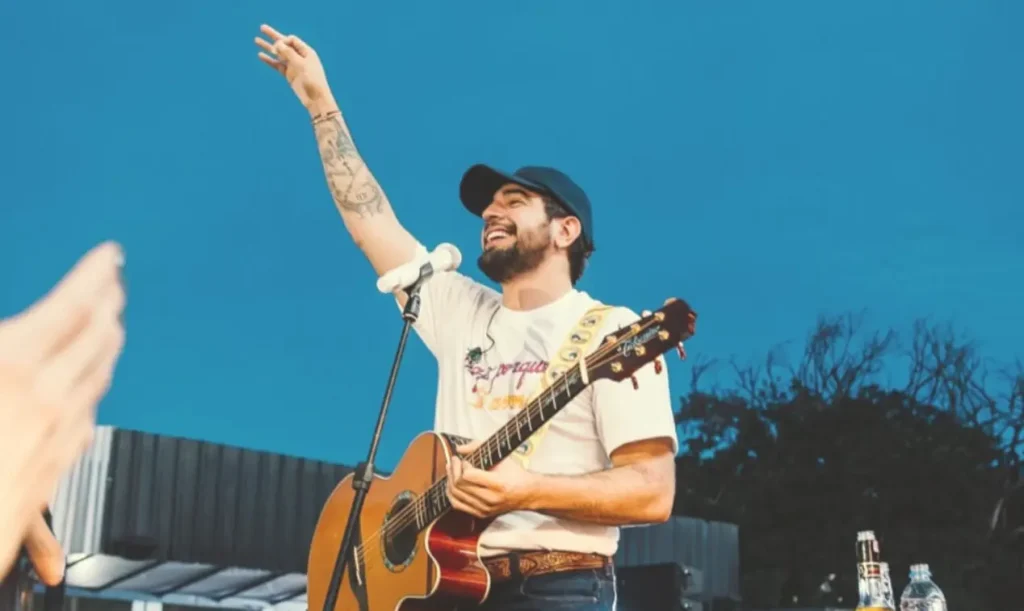 Show de nattan em campo maior suspenso: Cantor com violão levanta braço em show ao ar livre