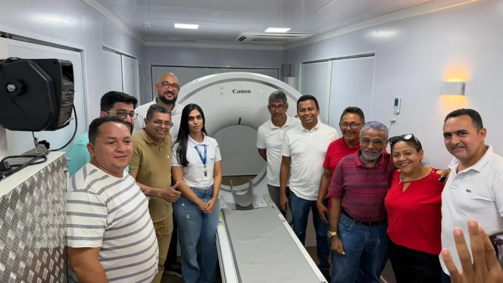 Carreta de Ressonância em Uruçuí: Grupo de 11 pessoas sorrindo dentro da carreta em frente a um tomógrafo Canon branco, em ambiente médico ou unidade móvel.
