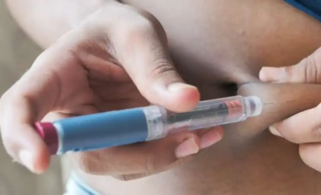 Canetas emagrecedoras na menopausa: Pessoa aplicando injeção de caneta no abdômen