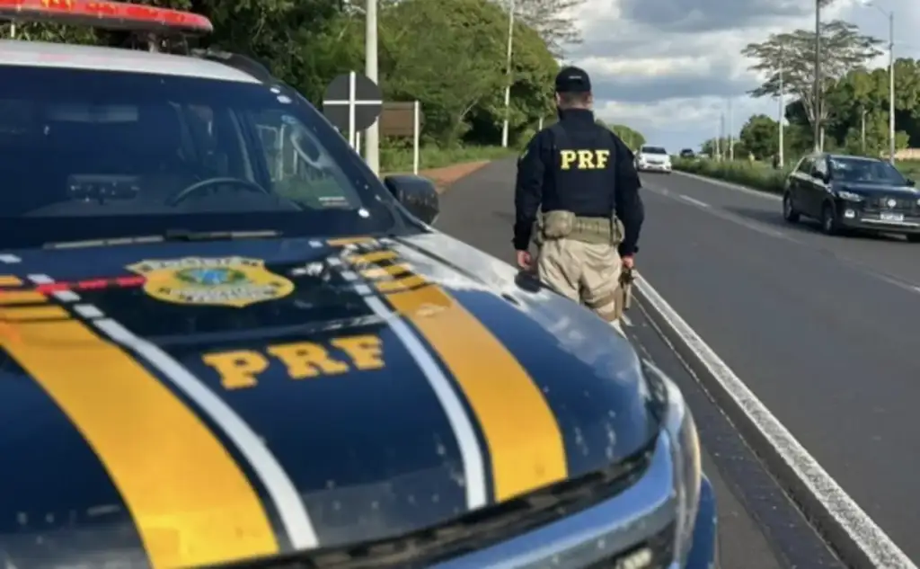 Fiscalização da prf no feriado de corpus christi 2026: Policial da PRF ao lado de viatura em rodovia