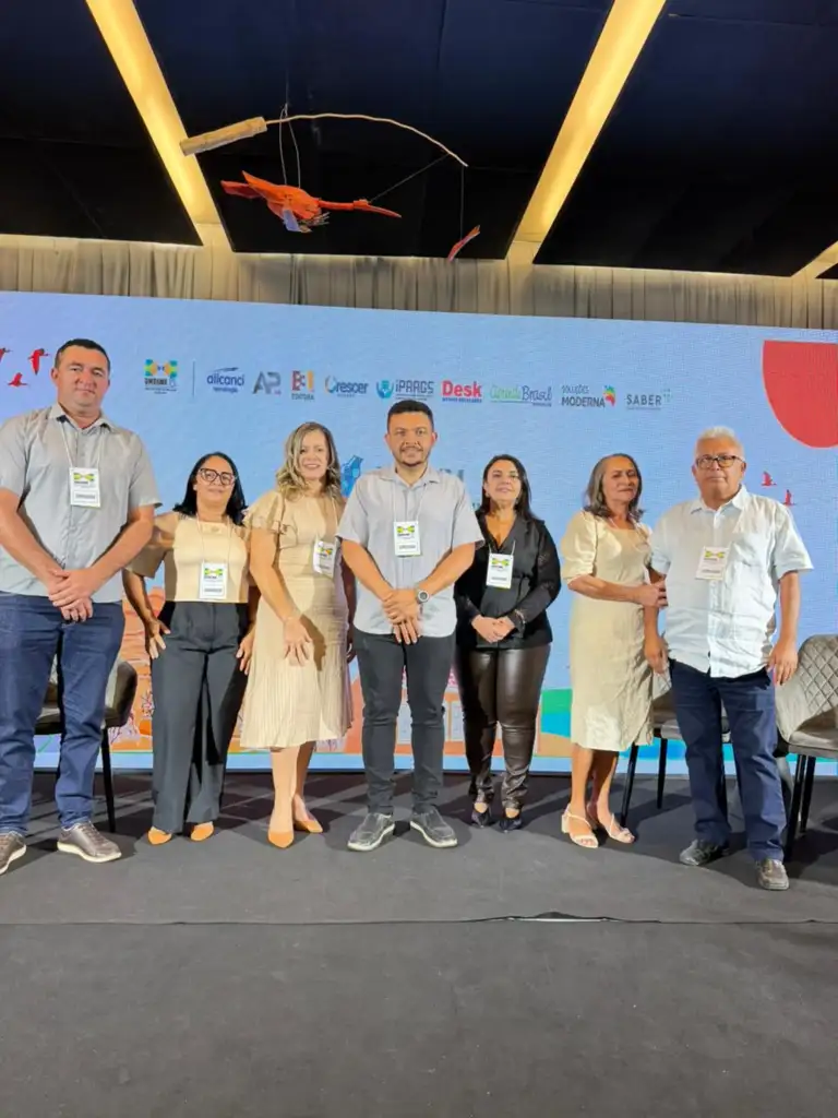 Grupo de palestrantes em palco de evento corporativo