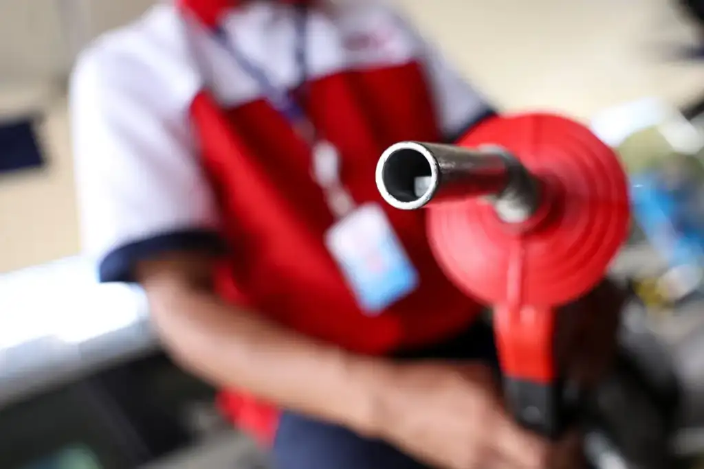 Petrobras corta preço do diesel: Frentista segurando bico de combustível vermelho