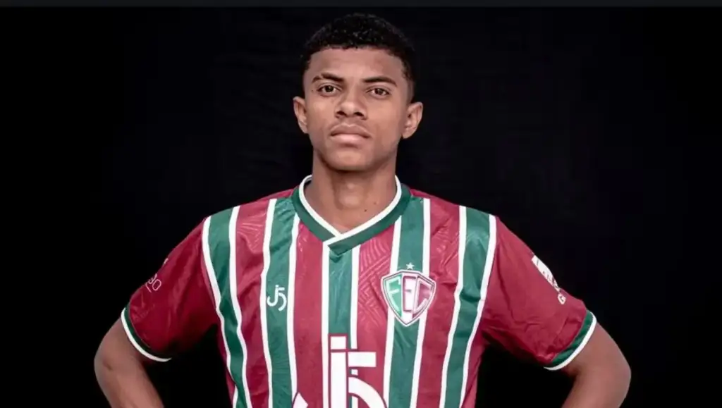 Jogador de futebol, Tilico posa com a camisa listrada em grená e verde do Fluminense, mãos na cintura, fundo preto