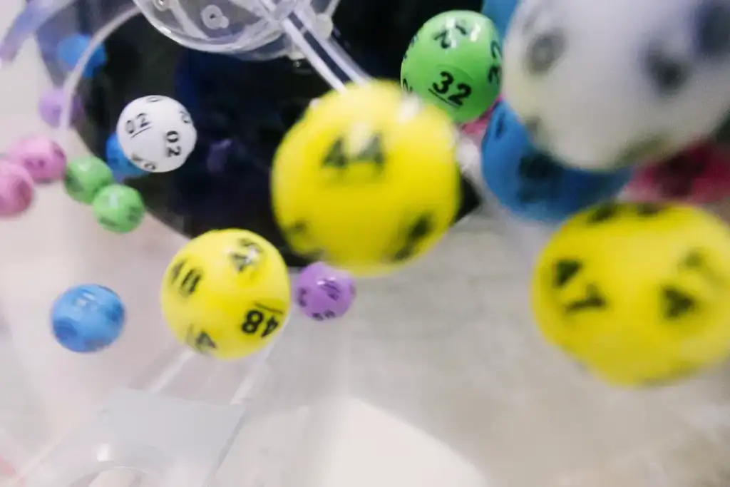 Bolas coloridas numeradas de uma máquina de sorteio de loteria, com números como 44, 48, 32 e 47 visíveis