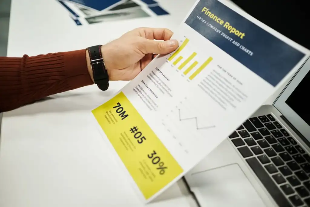 cliente segurando um relatório financeiro impresso com gráficos e dados, ao lado de um notebook aberto