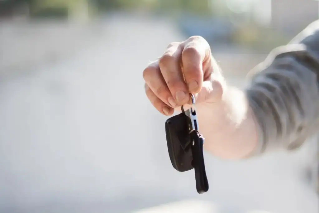 Mão estendida segurando chaves de carro com controle remoto